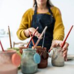 Close-up of a woman picking up paints at ceramics workshop